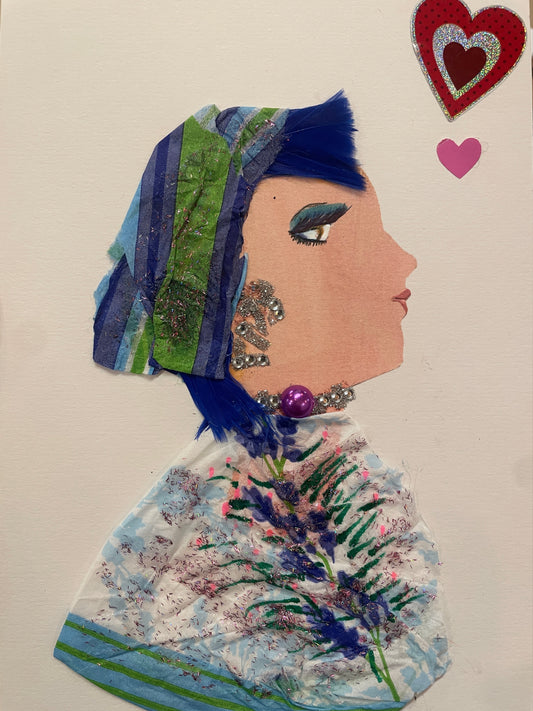 This is a handmade card of a woman named Irie Islington. She wears a striped head wrap, blue hair, and a glittered floral garment. Two heart stickers, one red and one pink, decorate the top right corner.