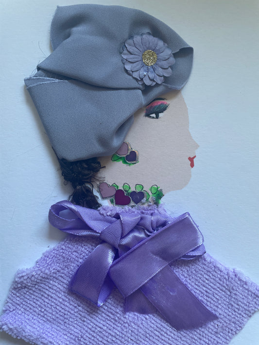 This is a handmade card of a woman named Julie Jolly. She wears a soft lavender headwrap decorated with a fabric flower that has a glittery gold centre. Her earring and necklace are painted with heart shapes in shades of purple and pink, surrounded by green beads. She is dressed in a textured lavender top with a satin bow at the collar. Her face is shown in profile, with red lips and eyeshadow in purple and green tones.