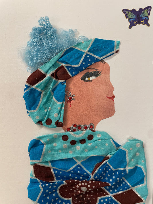 This is a handmade card of a woman named Laeticia Spitalfields. She has curly blue hair, wears a light blue and brown patterned outfit and wrap, and sparkly red jewellery.