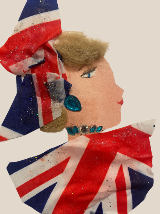 This is a handmade card of a woman named Millie Lionheart. She wears a glittery Union Jack outfit and a large red, white and blue bow in her hair, which is styled in a short, fluffy fringe. She has a teal earring and matching jewels at her neck.