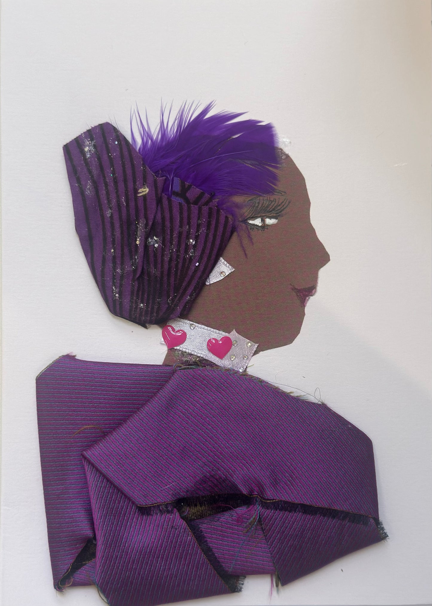 A handmade portrait of “Miraculous Manjula,” featuring a purple striped headscarf with violet feathers, a heart-patterned collar, and a folded purple satin wrap with subtle glitter accents.