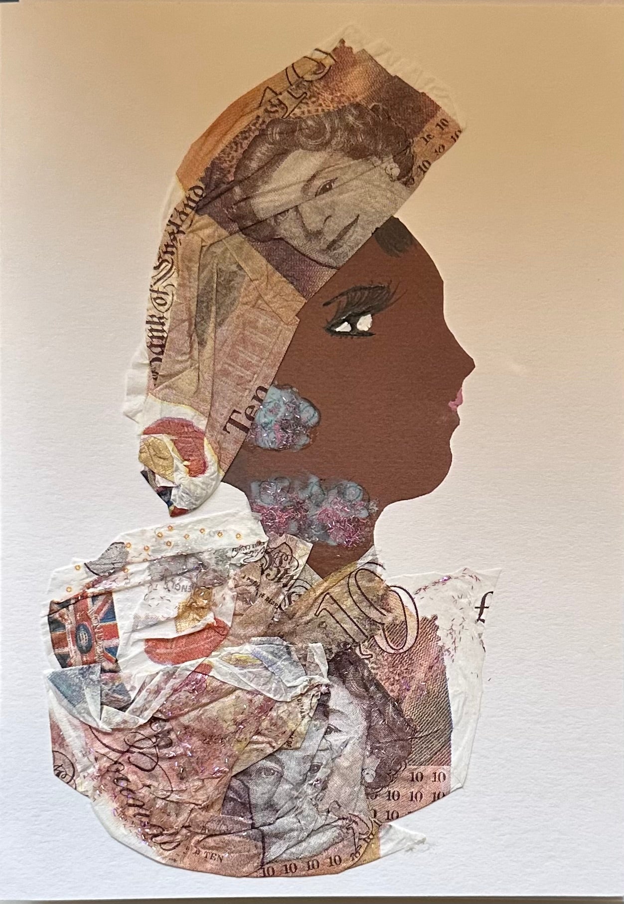 A handmade collage of a woman in profile composed of textured currency-themed paper. She wears a headwrap and garment made from layered banknote patterns, with a brown silhouette, detailed eye, and soft shading that highlights her strong and confident expression. The overlapping currency designs create a structured, geometric texture that forms both her hair wrap and clothing. The neutral tones of the paper contrast gently with the darker silhouette, giving the portrait depth.