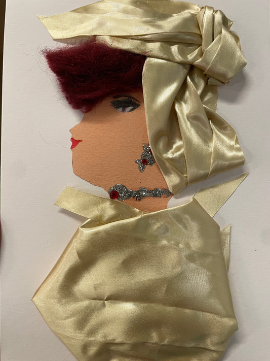 This is a handmade card of a woman named Serena Silkmore. She wears a shiny cream satin wrap and matching top, with a gem earring and necklace, and deep burgundy hair styled in soft waves.