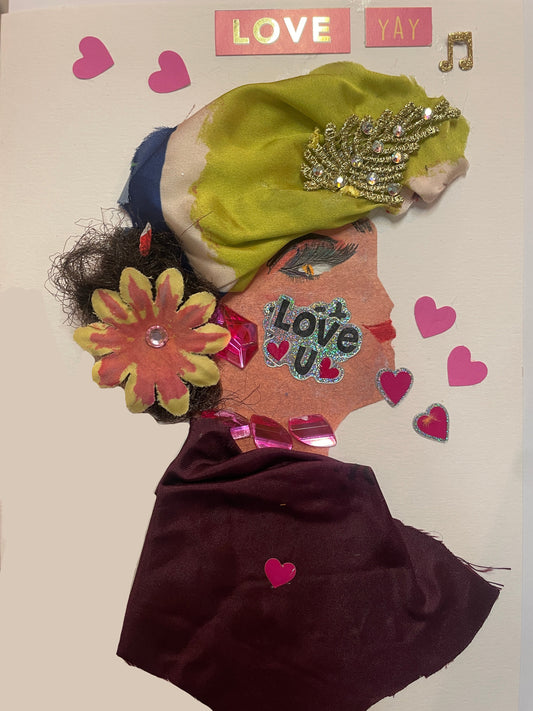 A handmade card of a woman in profile wearing a maroon dress, a yellow-green and navy head wrap with gold decoration, a pink flower on her shoulder, and surrounded by pink heart stickers and the word “LOVE”.
