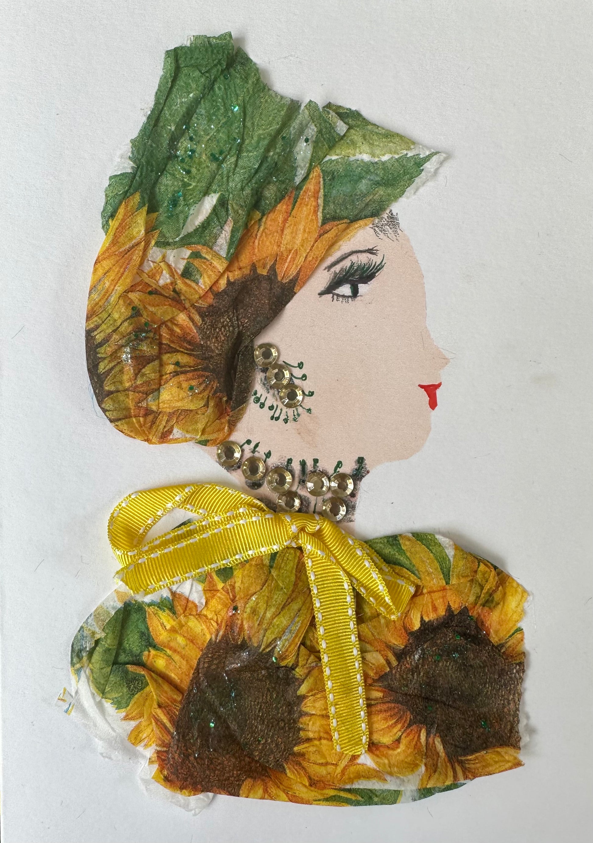 I designed this handmade card of a woman dressed in a sunflower patterned blouse and hatinator. The blouse has a yellow bow around the collar, and her jewellery is silver gemstones.