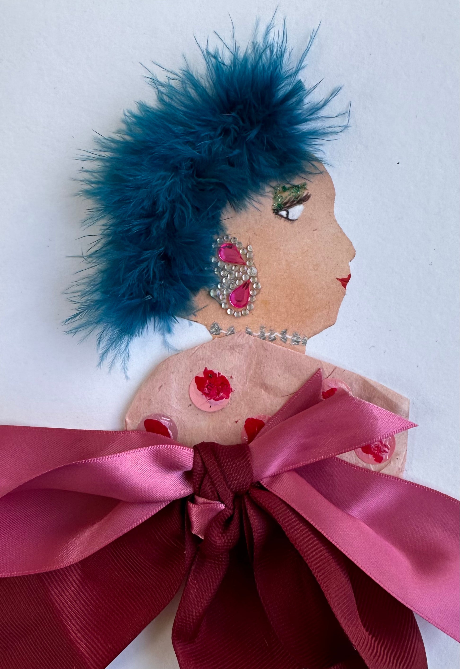 I designed this handmade card of a woman dressed in pink blouse that is made up of two pink bows. She has electric blue hair and pink gemstone jewellery, which matches her outfit.