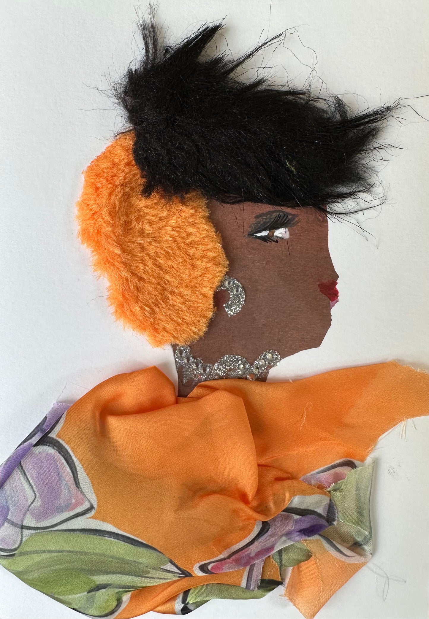 I made this handmade card of a woman dressed in an orange blouse that is patterned with lavender purple flowers with light, sage green leaves. Her hair is black on the top and orange towards the bottom. The outfit is finalized with diamond-like gemstones for her necklace and earrings.