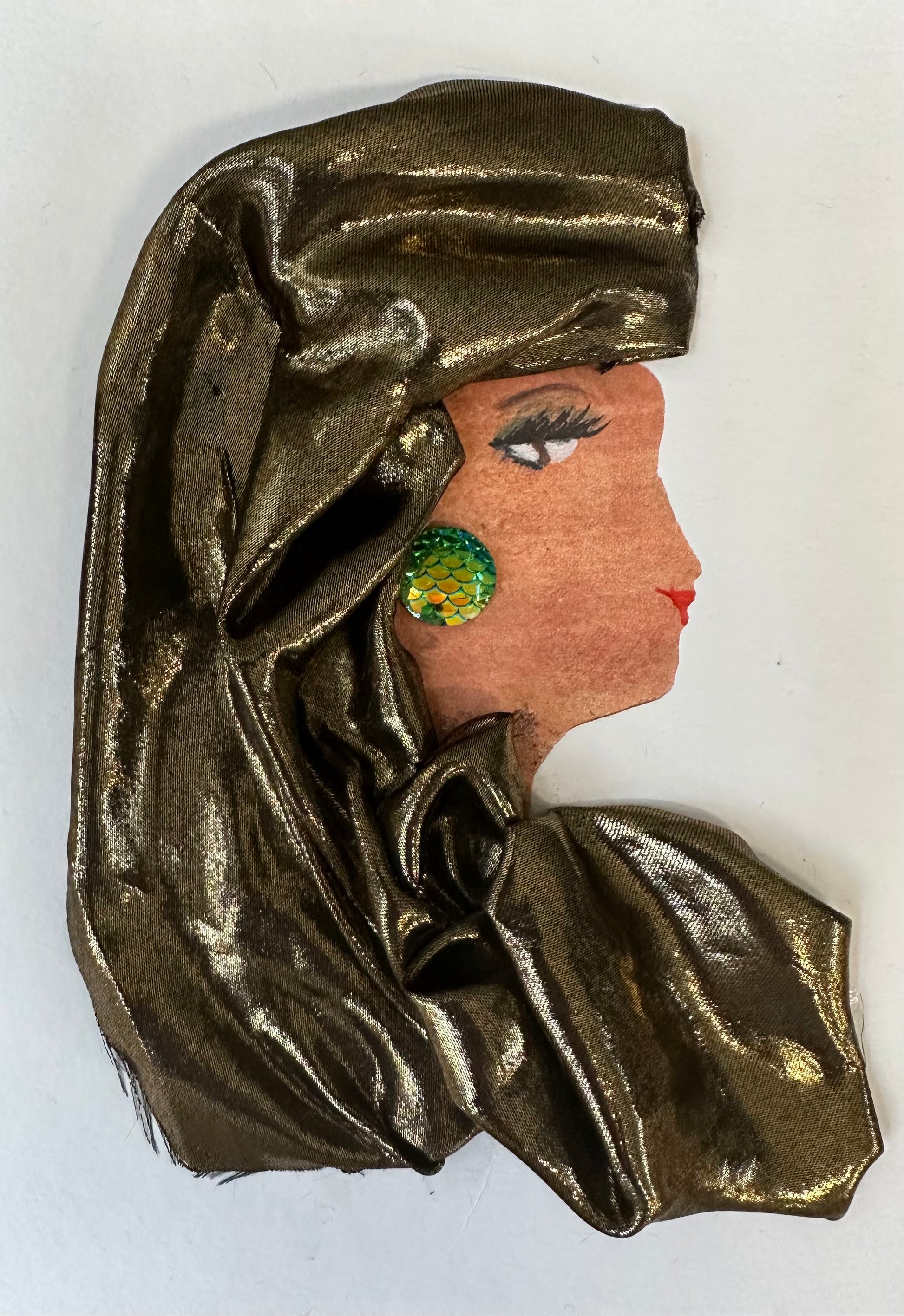 I created this handmade card of a woman dressed in a reflective bronze coloured blouse and hatinator. Her earring is a teal chromatic circle with a scale like texture. 