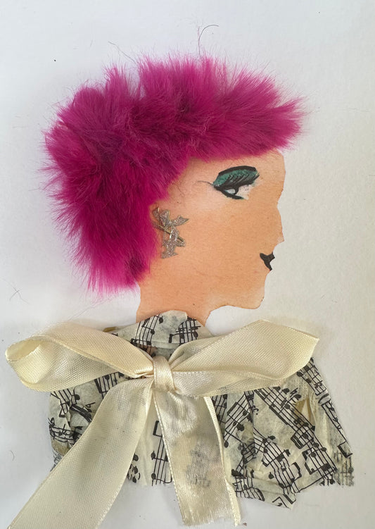I designed this handmade card of a woman dressed in a blouse that is patterned with a music sheet. Her blouse is tied together with a cream-coloured bow. She has electric pink hair and silver earrings. Her outfit is completed with her greenish blue eye shadow. 