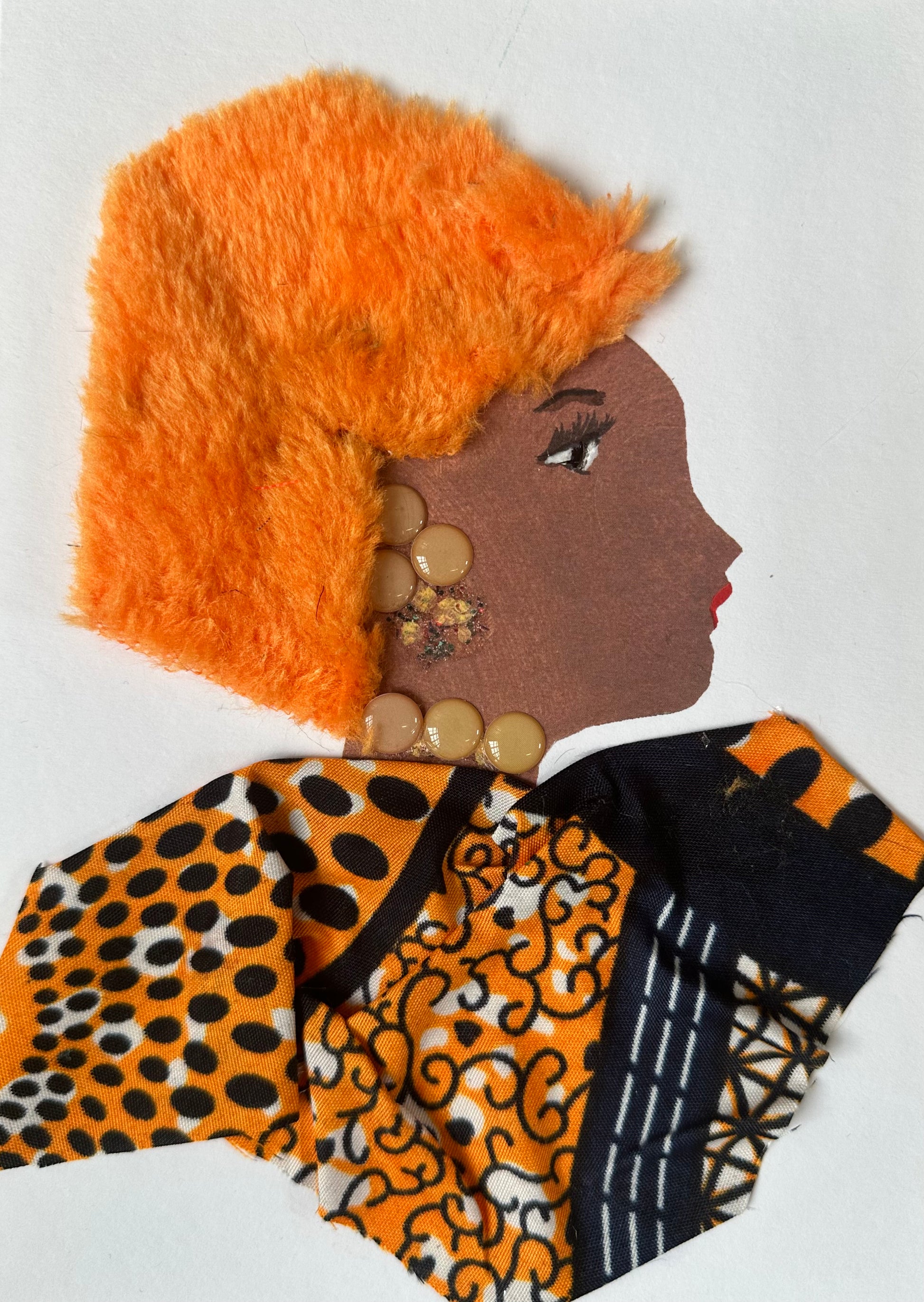 I designed this handmade card of Tottenham Tami. She is dressed in an orange and black ankara which complements her bright orange hair. The outfit is completed with a soft walnut coloured set of earrings and necklace.