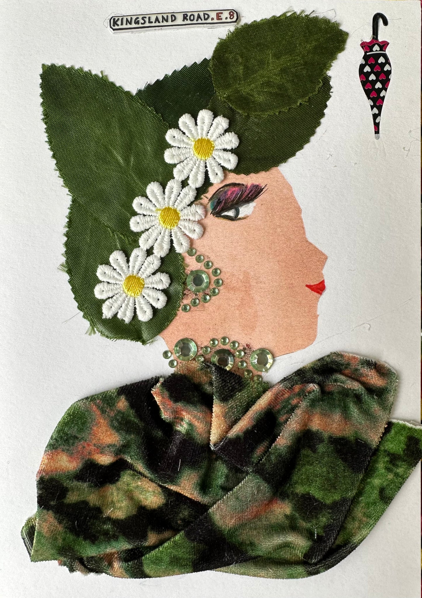 I made this handmade card of a woman dressed in a green top that has hints of orange. The outfit is complimented by matching green gemstone earrings and a necklace. In her hair, there are green leaves and daisies. 