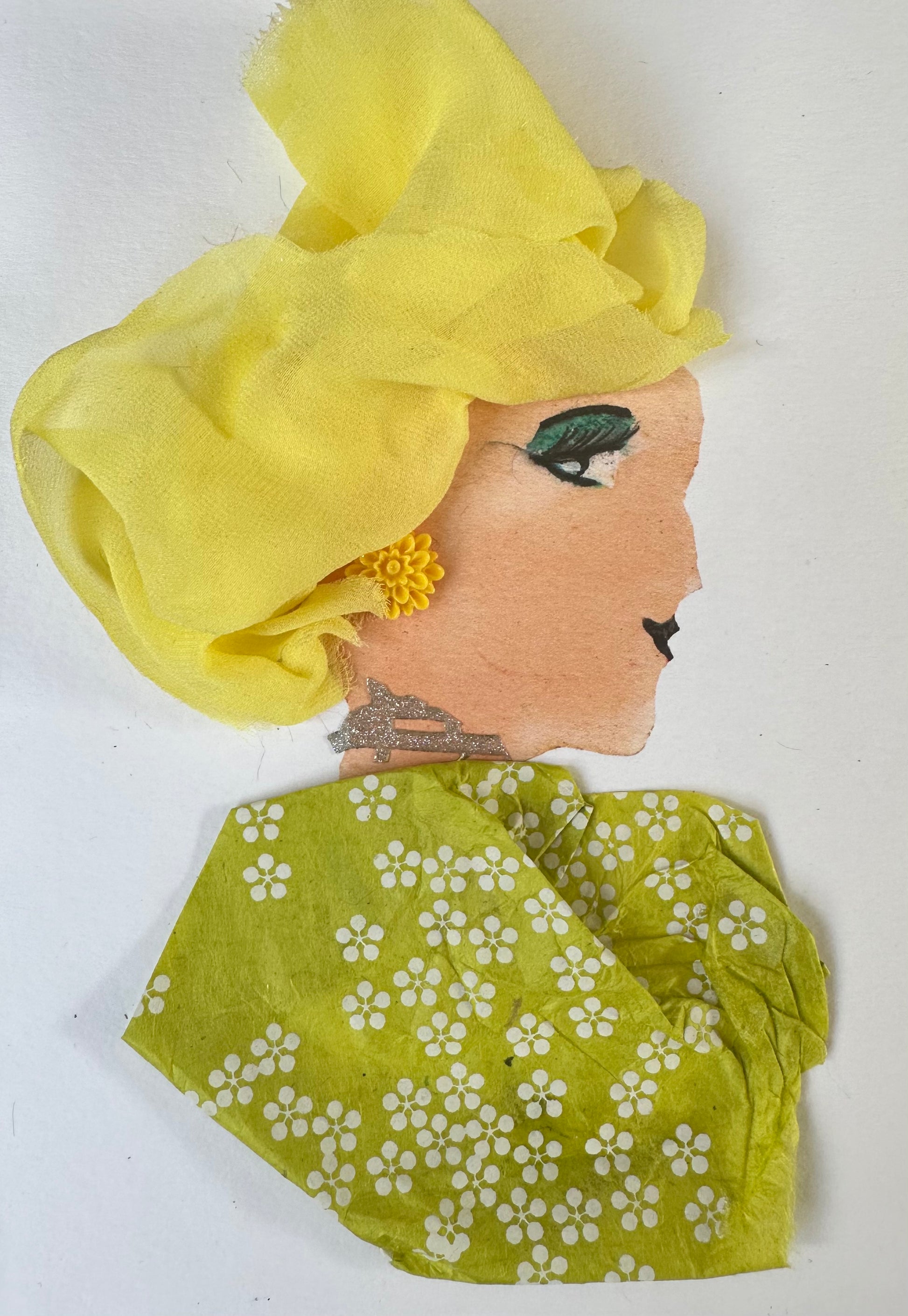I designed this handmade card of a woman dressed in a yellow blouse with green undertones; it is patterned with small white flowers. She is wearing a bright yellow hatinator and yellow flower shaped earrings. Finally, she is wearing a dark green eye shadow.