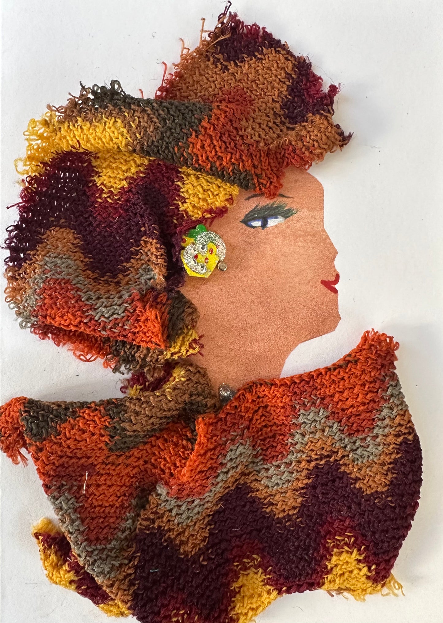 I designed this handmade card of a woman dressed in a burnt orange, burgundy, yellow, and other fall colour blouse and hatinator. They are btoh a knitted material. Her earring is a brighter yellow.