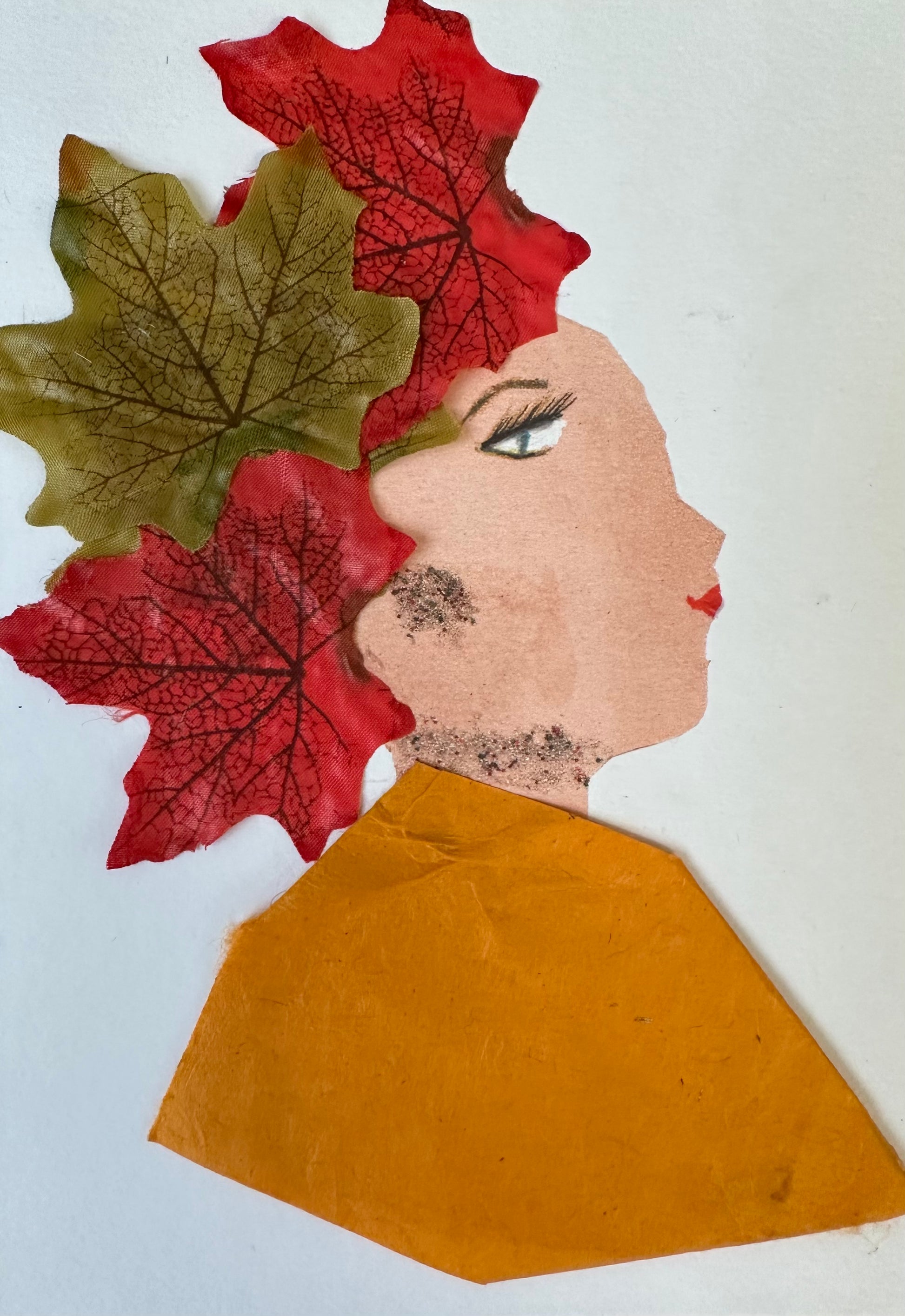 I designed this handmade card of a woman dressed in an orange blouse. Her hair is made up of three leaves, two that are red and one is green. She has jewellery that is composed of small dots.