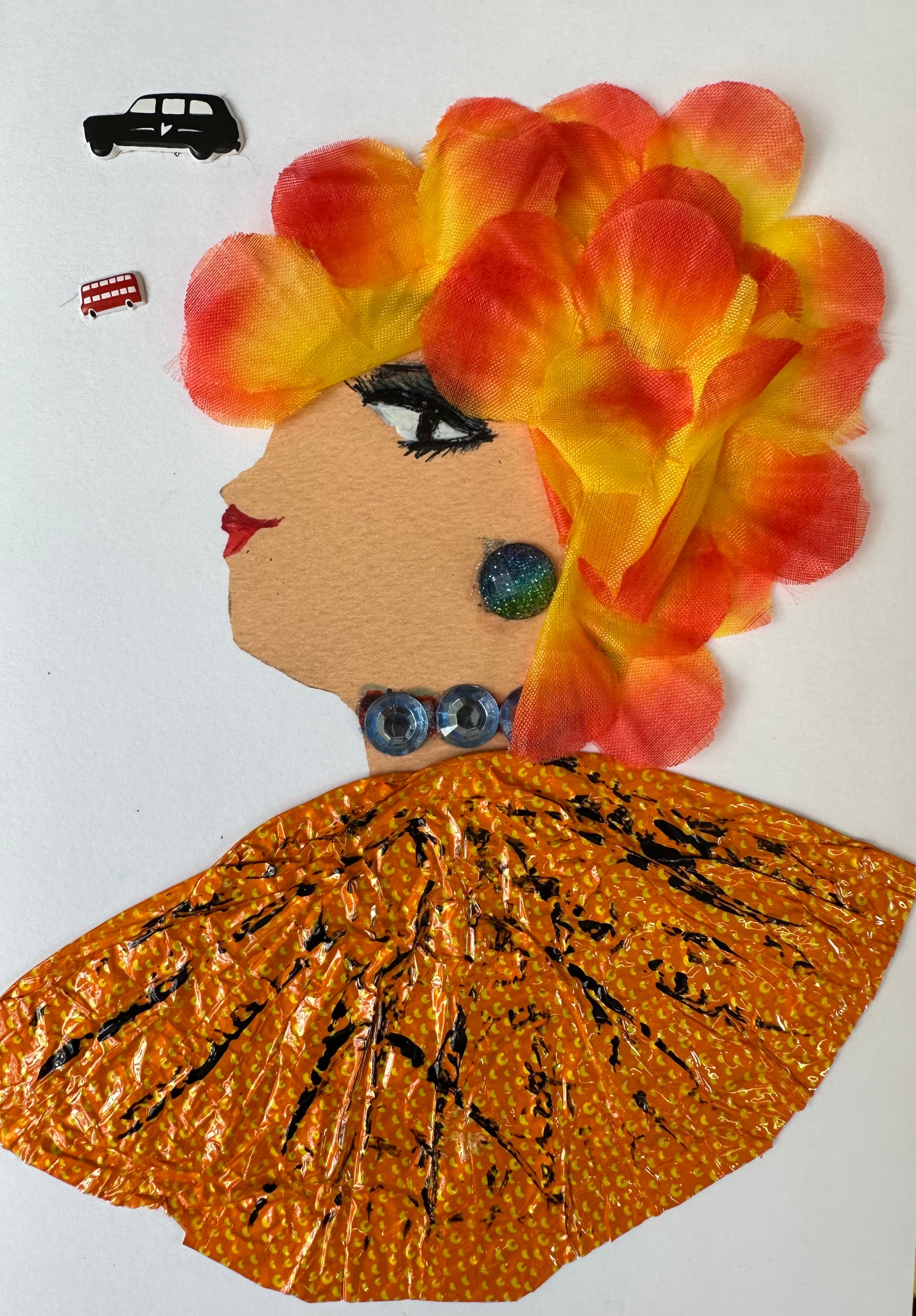 This handmade card of Kilburn Kelly is of a woman dressed in an orange blouse with black stripes and small yellow dots. Her hair is bright orange and yellow ombre petals. Her outfit is completed with blue gemstone jewellery. Finally, there is a black car in the left corner of the card.