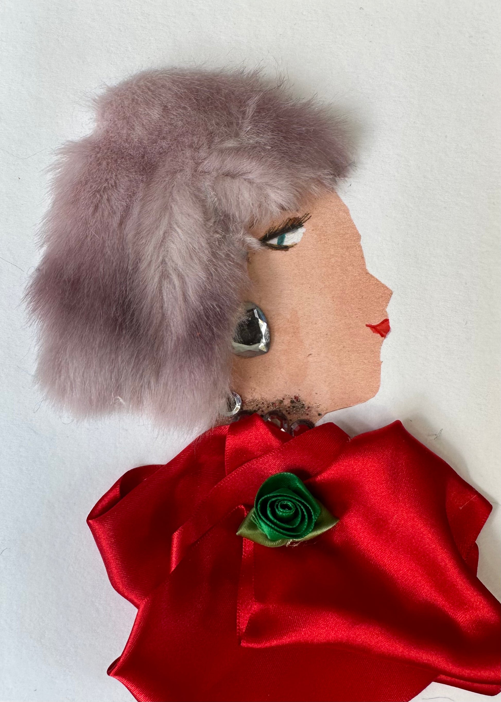 I designed this handmade card of woman dressed in a red, silk-like blouse with an emerald green flower in the center. She has a soft purple coloured hair and silver heart-shaped earrings.