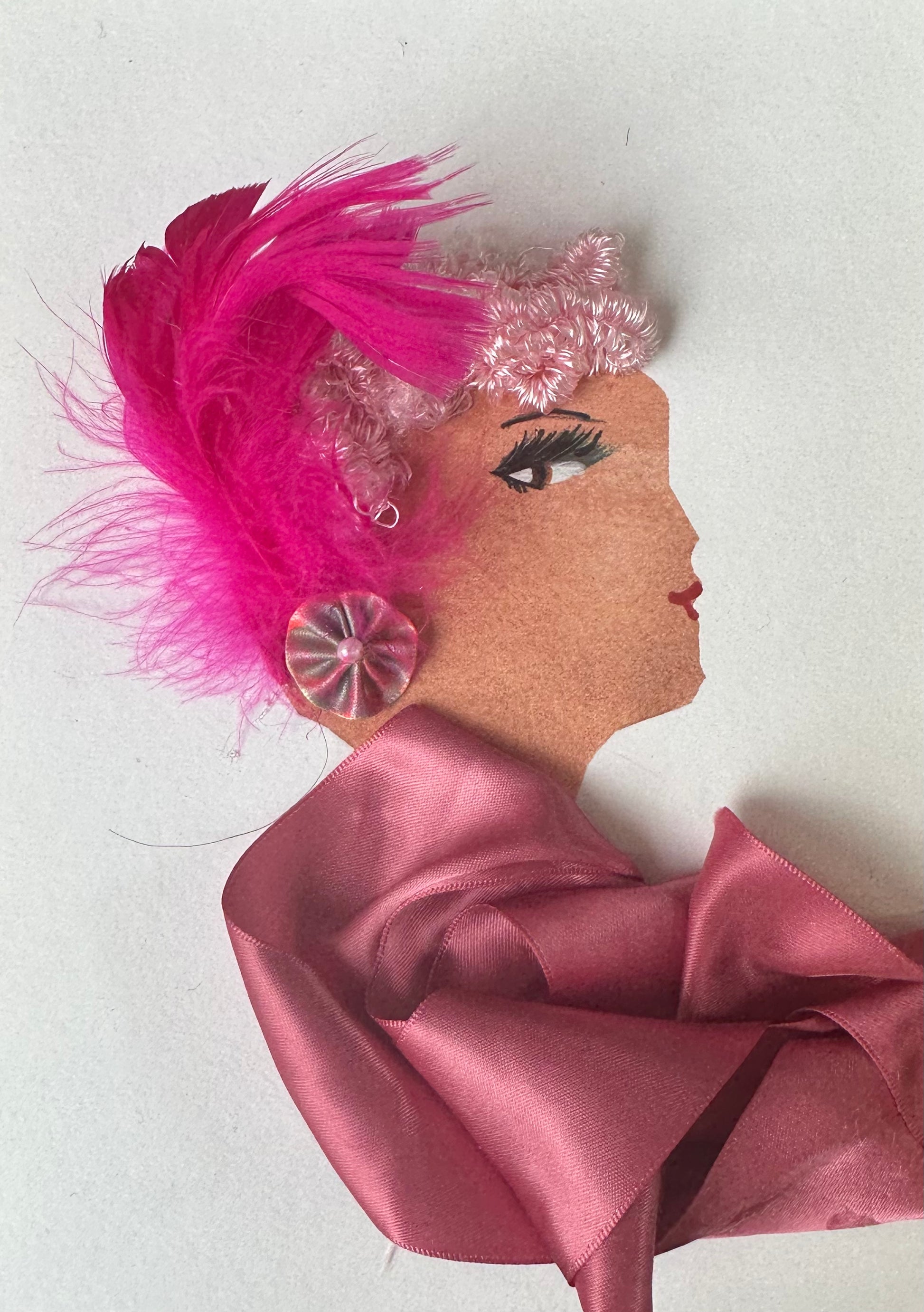 I designed this handmade card of a woman dressed in a pink ribbon blouse. She had ballet pink hair that is pinned back with an electric pink flower. The outfit is completed with a flower shaped earring with a pearl-like center.