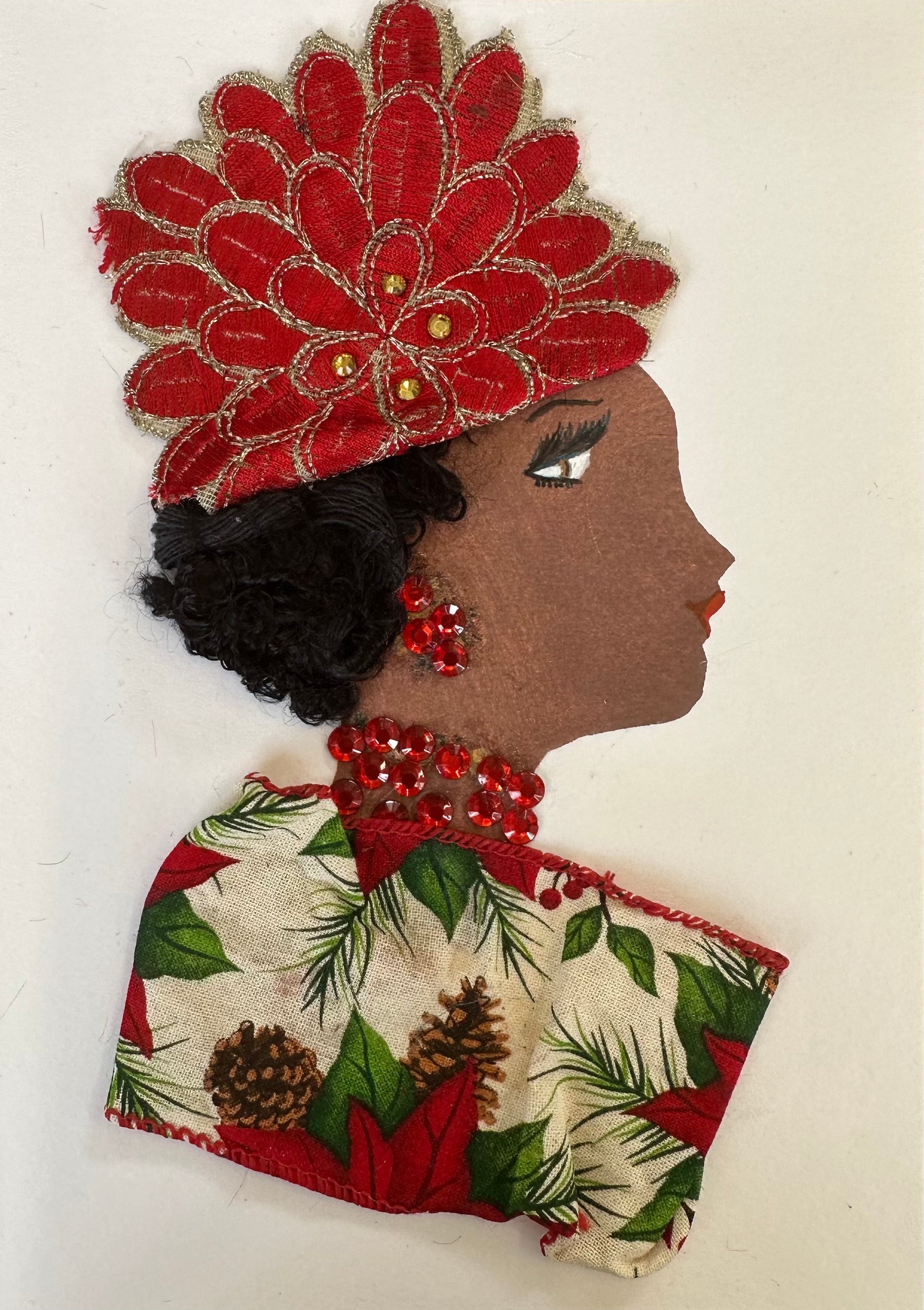 I designed this handmade card of Paddington Phoebe. She is wearing a beige coloured blouse with a red trim and patterned with poinsettias and pine cones. Her hatinator is a red flower like shape with gold outlines. The outfit is completed with ruby red, gemstone jewellery.