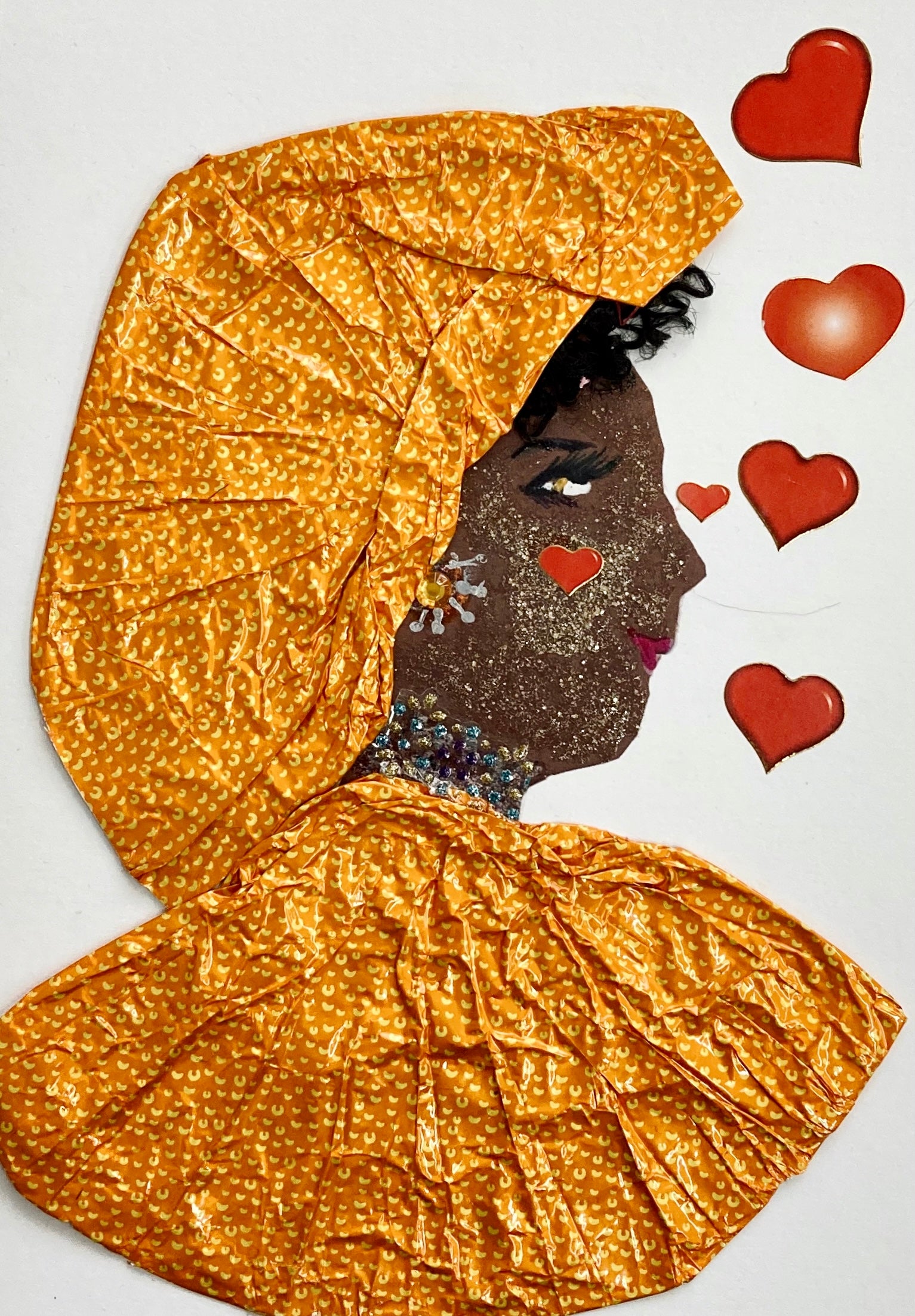 This card is called Octavia Orange. She wears a matching headdress and blouse, both which are made from an orange tin foil. Her face is covered in gold glitter, and she is surrounded by red hearts. 