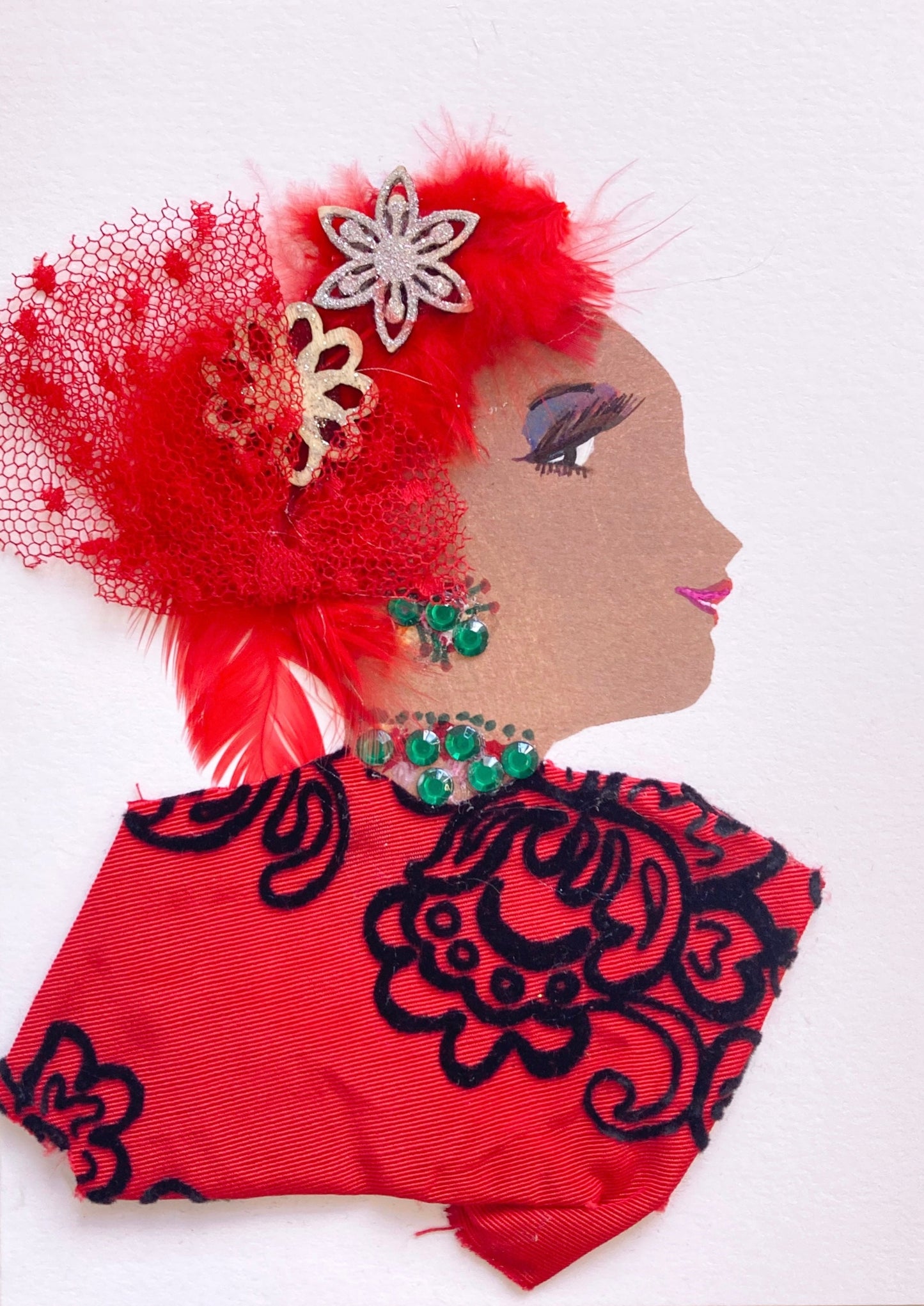 This card has been given the name Red Rebecca. Rebecca wears a blouse made of a red fabric with black embroidery. Her jewellery is green gems. She wears Flowers in her red feathery hair and a red mesh bow as well. 