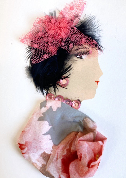 This card has been given the name belinda. She wears a floral blouse which has a grey background and pink roses on it. Her jewellery is made up of pink gems, and she wears a pink netted headpiece in her short black hair.