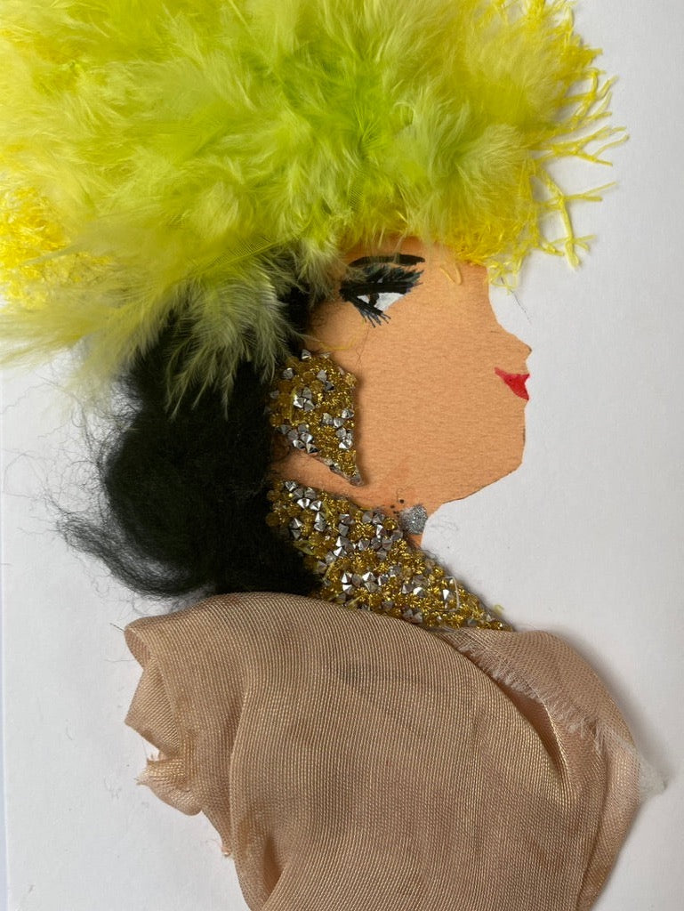 In this artistic card , Gill wears a nude coloured blouse and gold diamanté jewellery. She wears an explosion of lime green feathers as her  crown in her long black hair. 