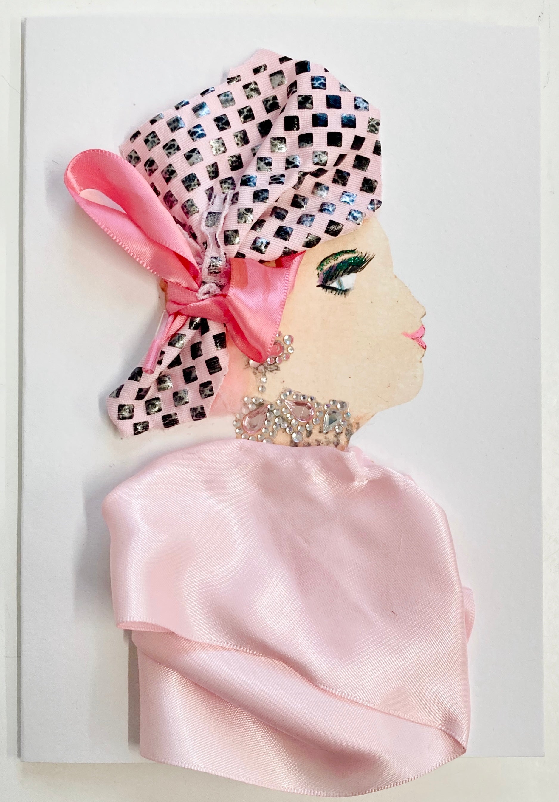 Peggy Paddington is accessorized with a light pink headpiece featuring silver diamanté squares and a hot pink bow, as well as a diamanté necklace and earrings.