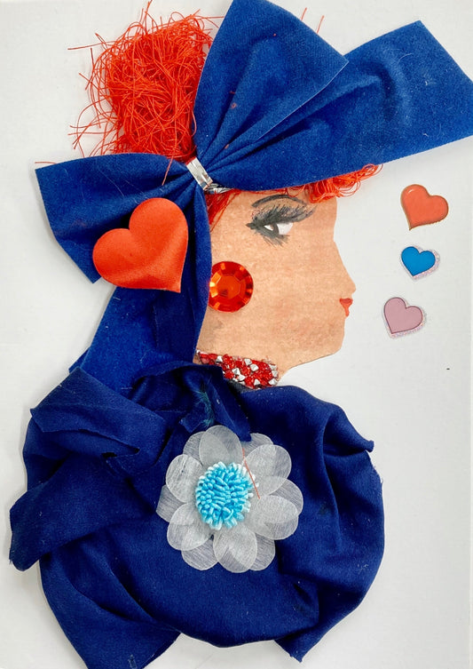 This card has. been given the name Holly. Holly wears a dark blue dress made of a lightweight fabric which has a large white flower pendant in the middle. She wears a large blue bow in her vibrant red hair, and on top of the bow there is a large red heart. Her earring is a large red gem, and her necklace is a cluster of small white and red diamonds. To the right of her, there are red, blue, and pink hearts.