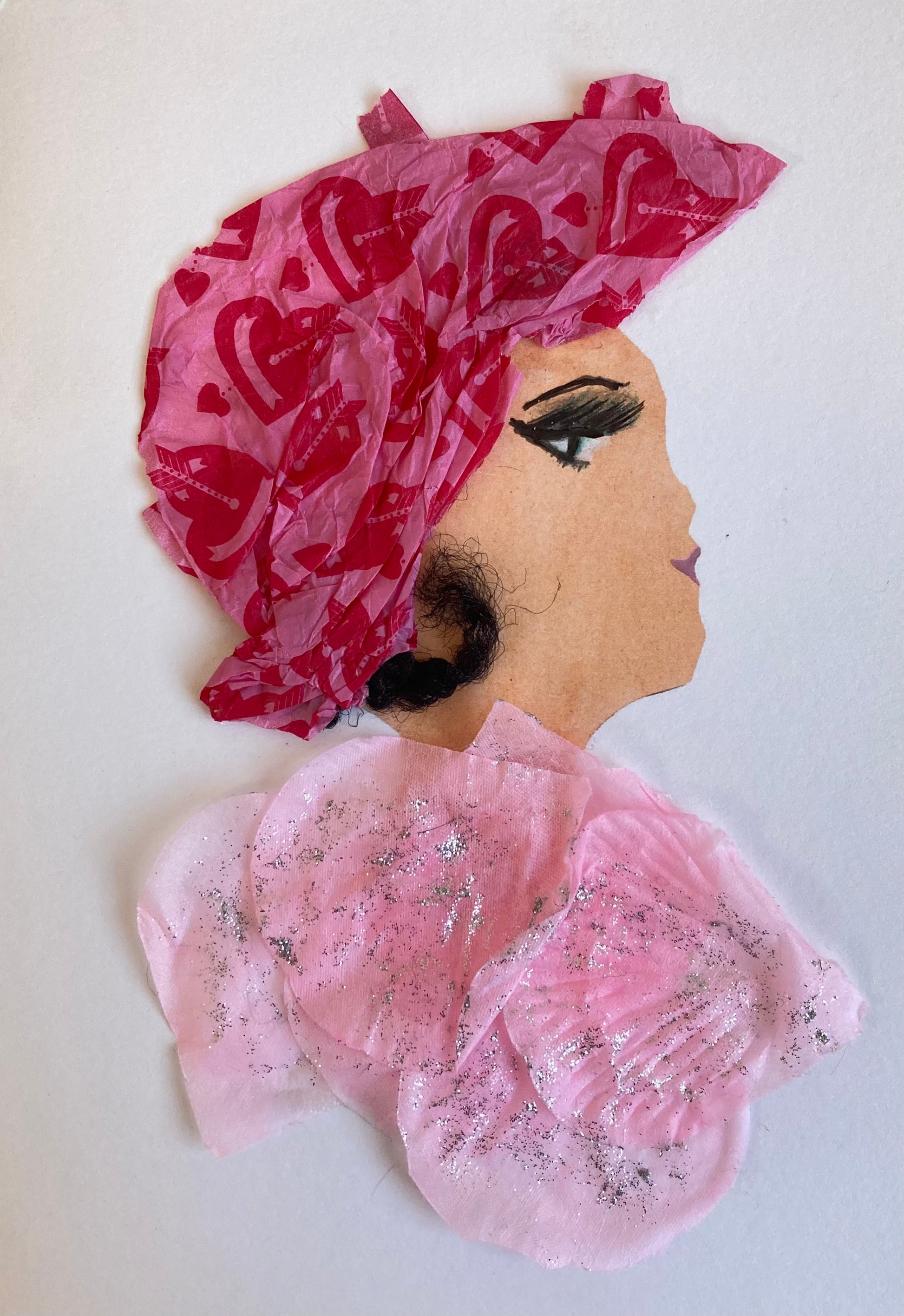 Poppy Portobello's ensemble includes a light pink top adorned with silver sparkles and a head-wrap of bright pink featuring red hearts, with a curl of her dark tresses artfully left visible.