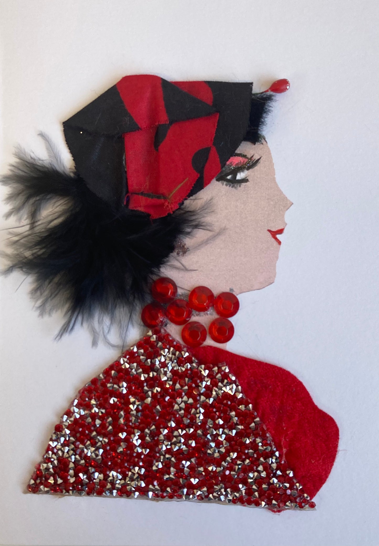 This card has been given the name Helvetica. She wears a blouse made of red and silver diamantés, a necklace made of red gems, and a small red and black headscarf in her feathery black hair. , 