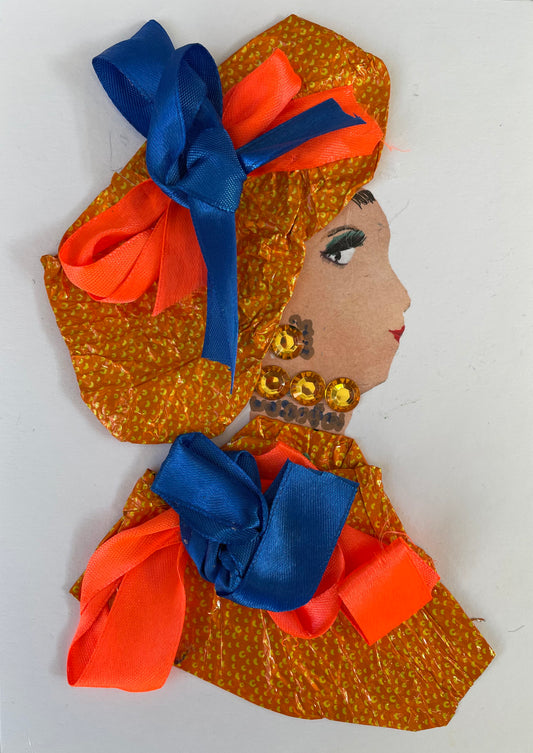 I have designed Alperton Anna to be wearing a shiny orange and gold dotted patterned blouse with an orange and blue bow. She has 2 jewel like necklaces on: one gold diamanté and one painted grey/blue with a matching pair of earrings. Her headpiece matches her blouse as it is the same material as well as the same orange and blue bow. 