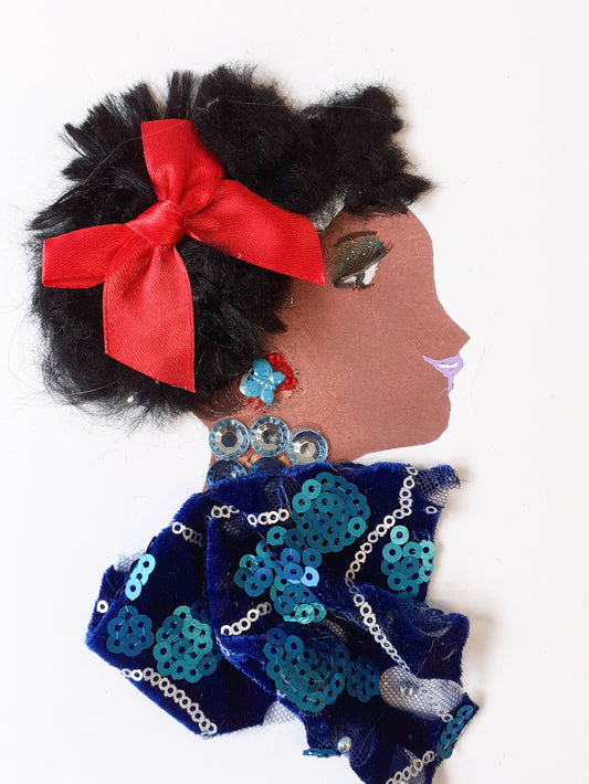 I designed this card of a woman named Doctor Jollof. She has a brown skin tone and is wearing a deep blue dress with a sparkling sapphire necklace matching her dress.