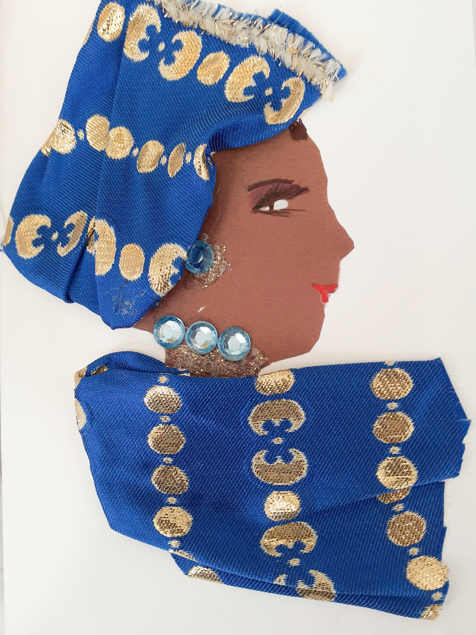 This card is of a woman given the name Doctor Rowanda Kenya. Rowanda wears a matching blouse and headscard, both a medium blue colour with gold circle printed on top. Her jewellery is light blue gems. 