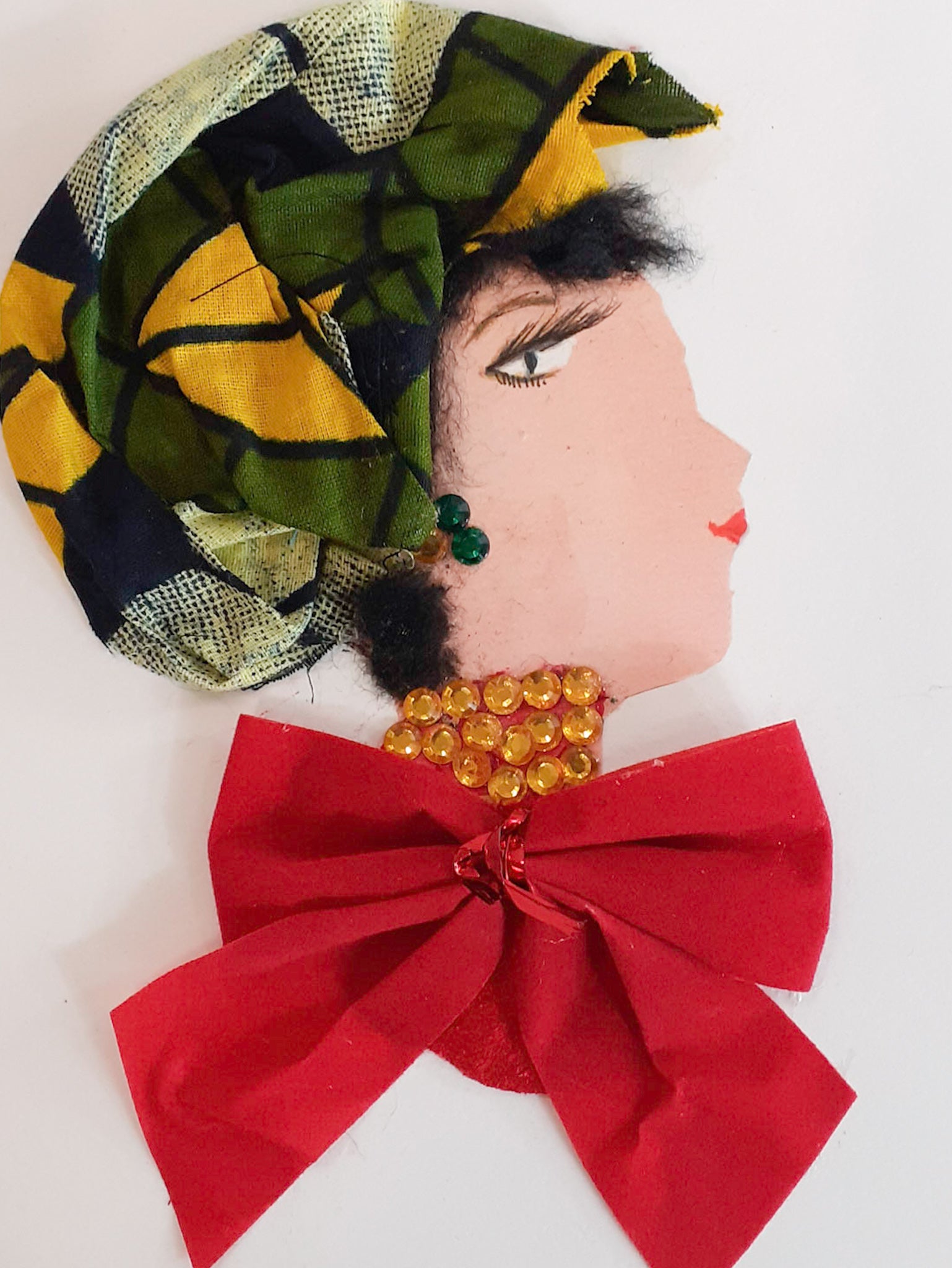 This card is of a woman named Angelina. Angelina wears a red top which is an oversized red bow. Her necklace is made of small yellow jewels, and she wears a headscarf with green and yellow geometric shapes on it. 
