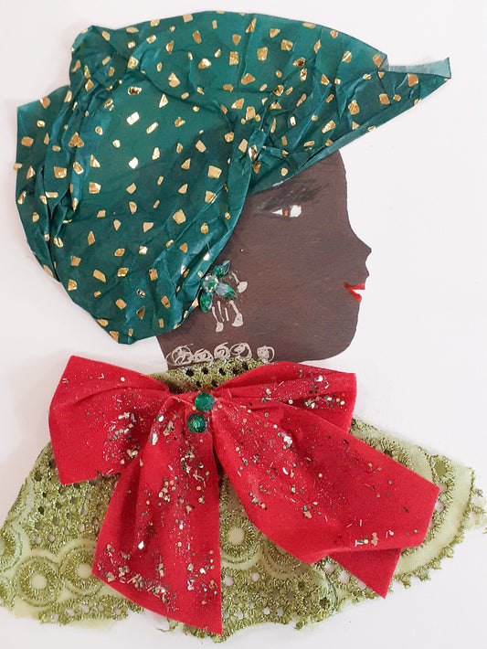 This card is named Cherry Christmas. She wears a green eyelet fabric dress with a large red bow covered in silver sparkles on top. Her headscarf is dark green and has a gold fleck pattern to it.