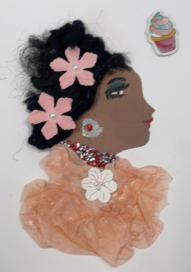This card is given the name Peach Princess. She wears a blouse made of a peach coloured tissue paper, and it has a white flower pendant that has small pearls in the center. Her jewellery is made up of red and silver diamantés, and She has two baby pink flowers in her curly black hair. On the top right corner, there is a cupcake sticker. A beautiful card  to frame for your home or the perfect gift for someone to celebrate 