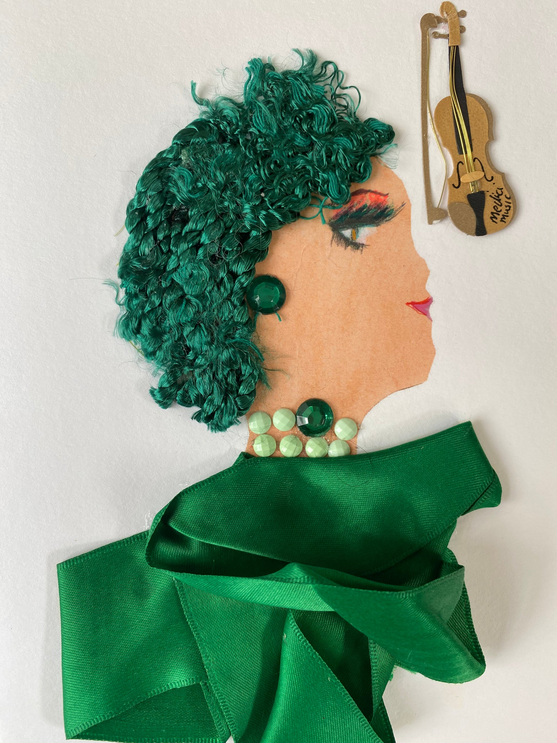 I designed this card of a woman named Musical Spinach. She has a white skin tone and has green curly hair. She wears a silky green blouse. She wears green gem jewellery. In the corner there is a violin.