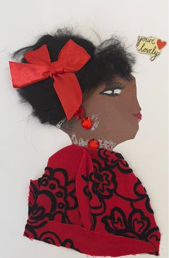 This card has been given the name Cinder Lovely. The woman is wearing a red fabric as her blouse with black flower embroidery on it. In her short black hair, she wears a satin red ribbon. Her jewellery is made from red gems. In the top right corner, there is a sticker that says "you're lovely."