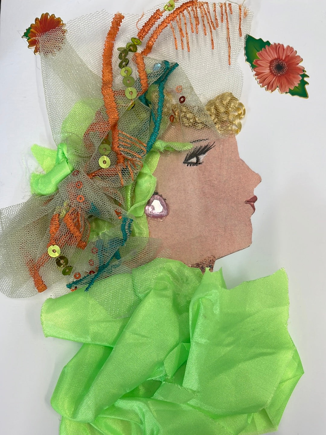 This card was given the name Meredith Grimsgate. She wears an electric green silky blouse, which match the material in her curly blonde hair. She also wears a sequin fabric headscarf which has orange accents. In the left and right corners, there are small orange flowers. 