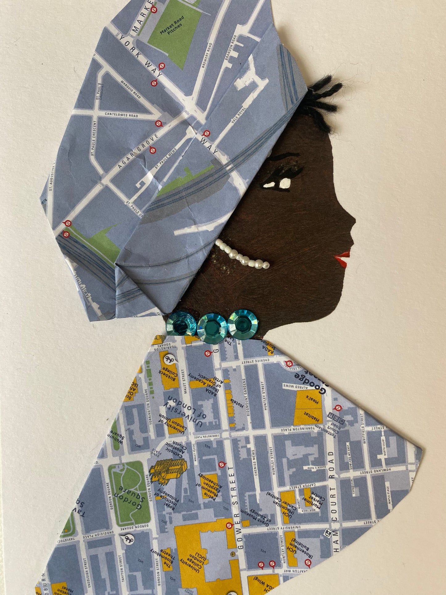 I designed this card of a woman named Juliette Jubilee. She has a black skin tone and is wearing a beautiful hat with a map print. She wears a matching map print blouse. She wears a pretty blue gem necklace and white dangling earrings. 