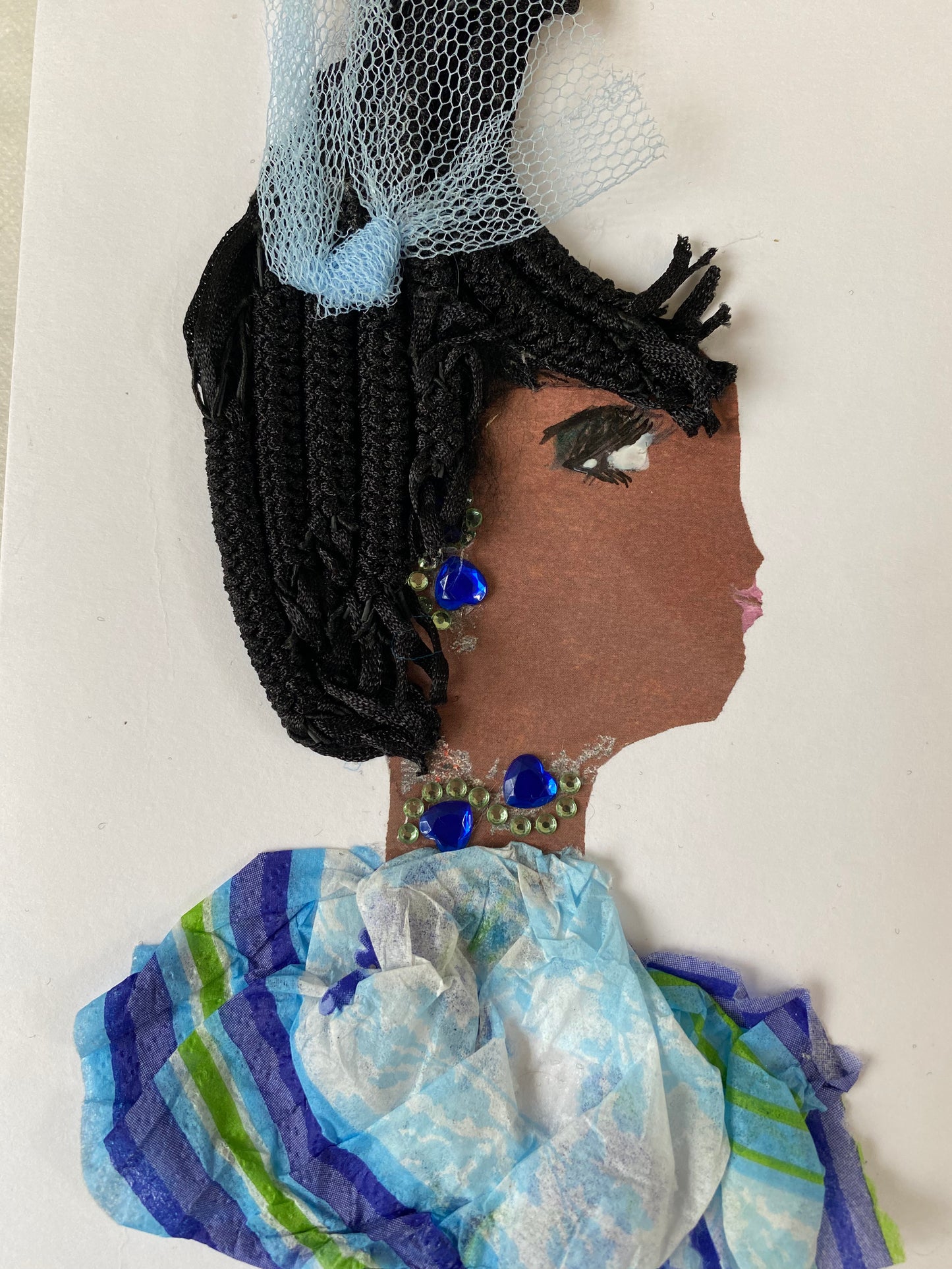 I designed this card of a woman named Bridget Blue. She has a brown skin tone who wears a blue fascinator hatinator. She wears a blue stripe blouse with darling blue jewellery.This handmade card shows a woman wearing a blue-hatinator and a blue-striped blouse with coordinating blue accessories.