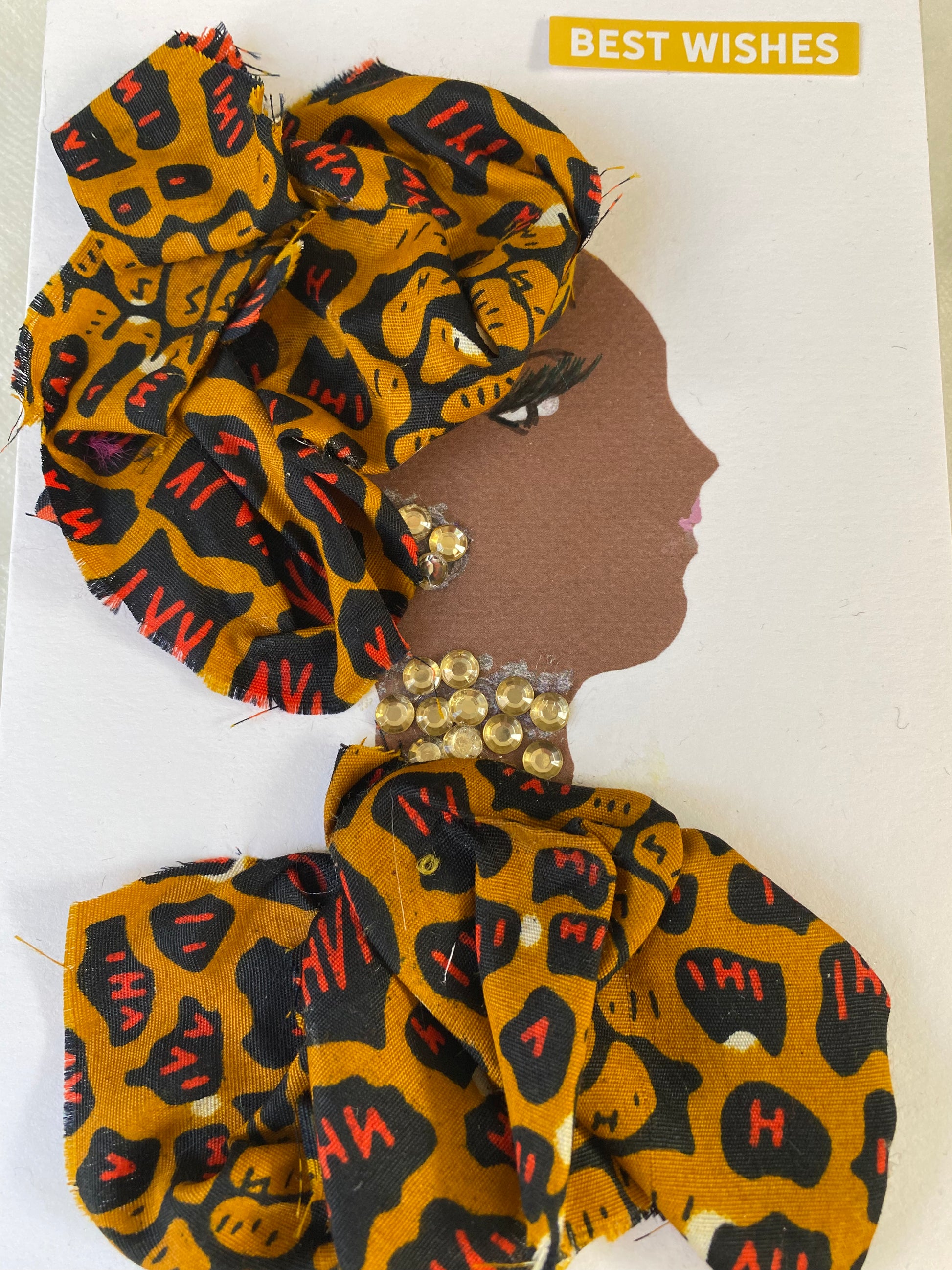 I designed this card of a woman named Chesham Chilly. She has a brown skin tone and wears a lovely patterned headwrap. She wears a gorgeous matching pattern blouse. She wears dazzling gold jewellery. In the corner it says "Best Wishes"