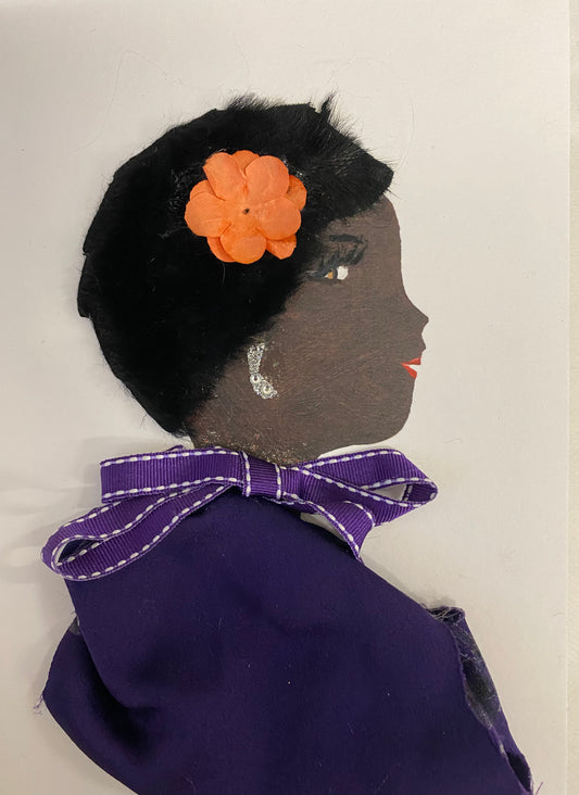 The design of this card features a woman adorned with a bright peach floral clip and a deep purple blouse, complemented by a delicate purple and white bow, as well as silver earrings for a touch of sparkle.