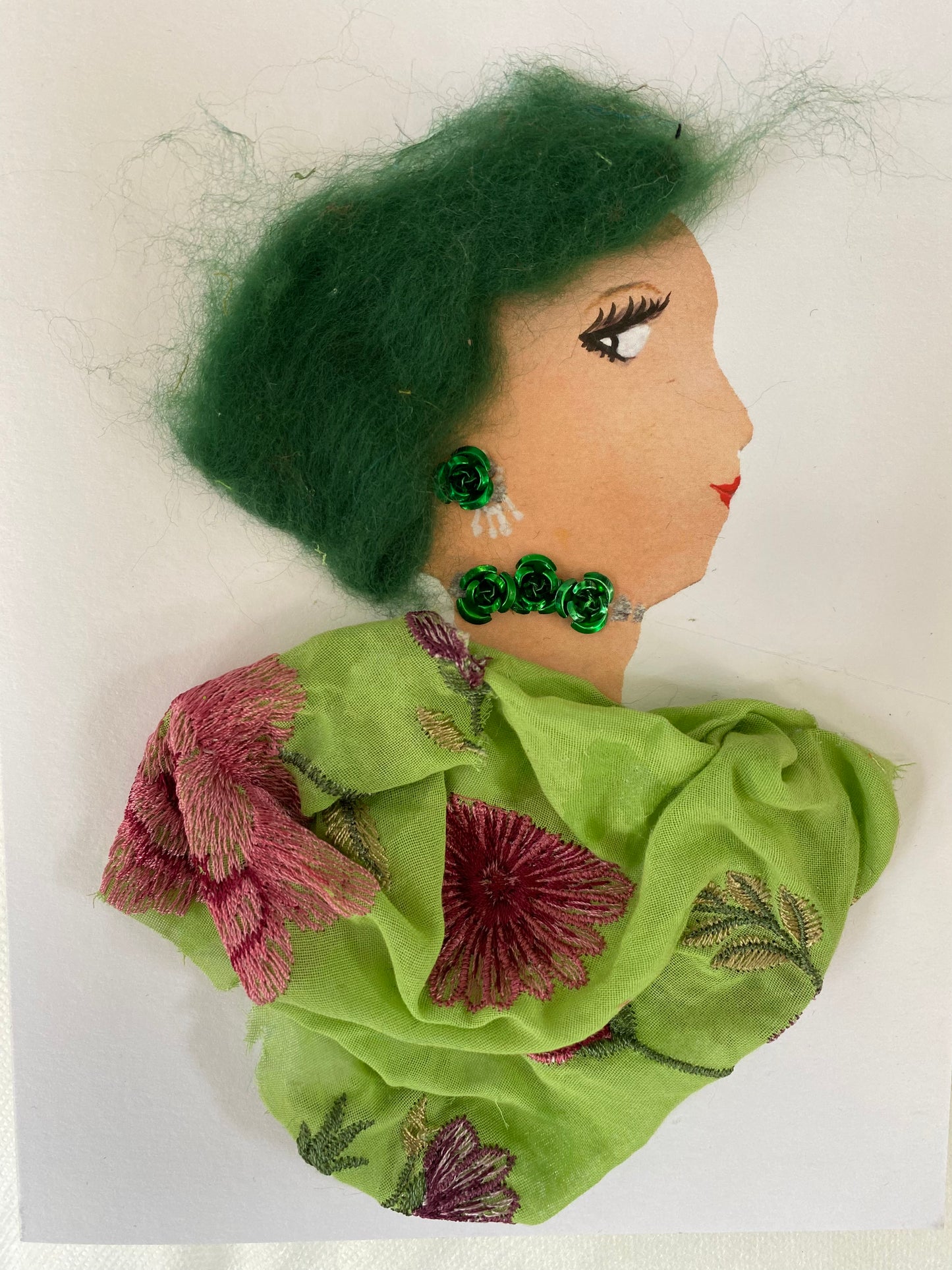 I designed this card of a woman named Genevieve Generous. She has a white skin tone and is wearing a green blouse with maroon flowers. She wears a necklace that has green roses on it. She wears matching green rose earrings.