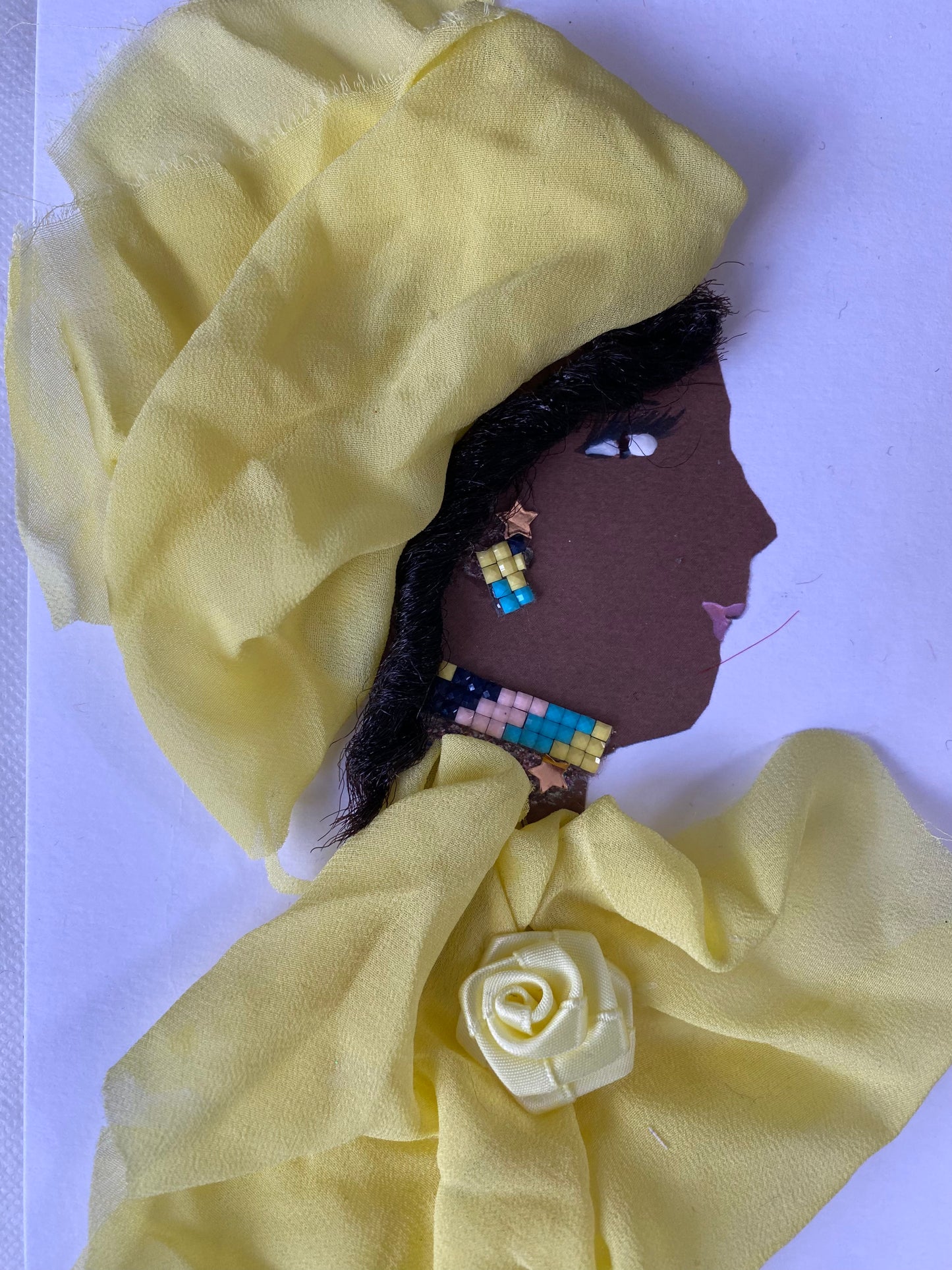 I designed this card of a woman named Dr. Boston Manor. She has a black skin tone and is wearing a delicate yellow head wrap. She is wearing a matching yellow blouse with a flower in the middle. She wears colorful jewellery to finish the look.