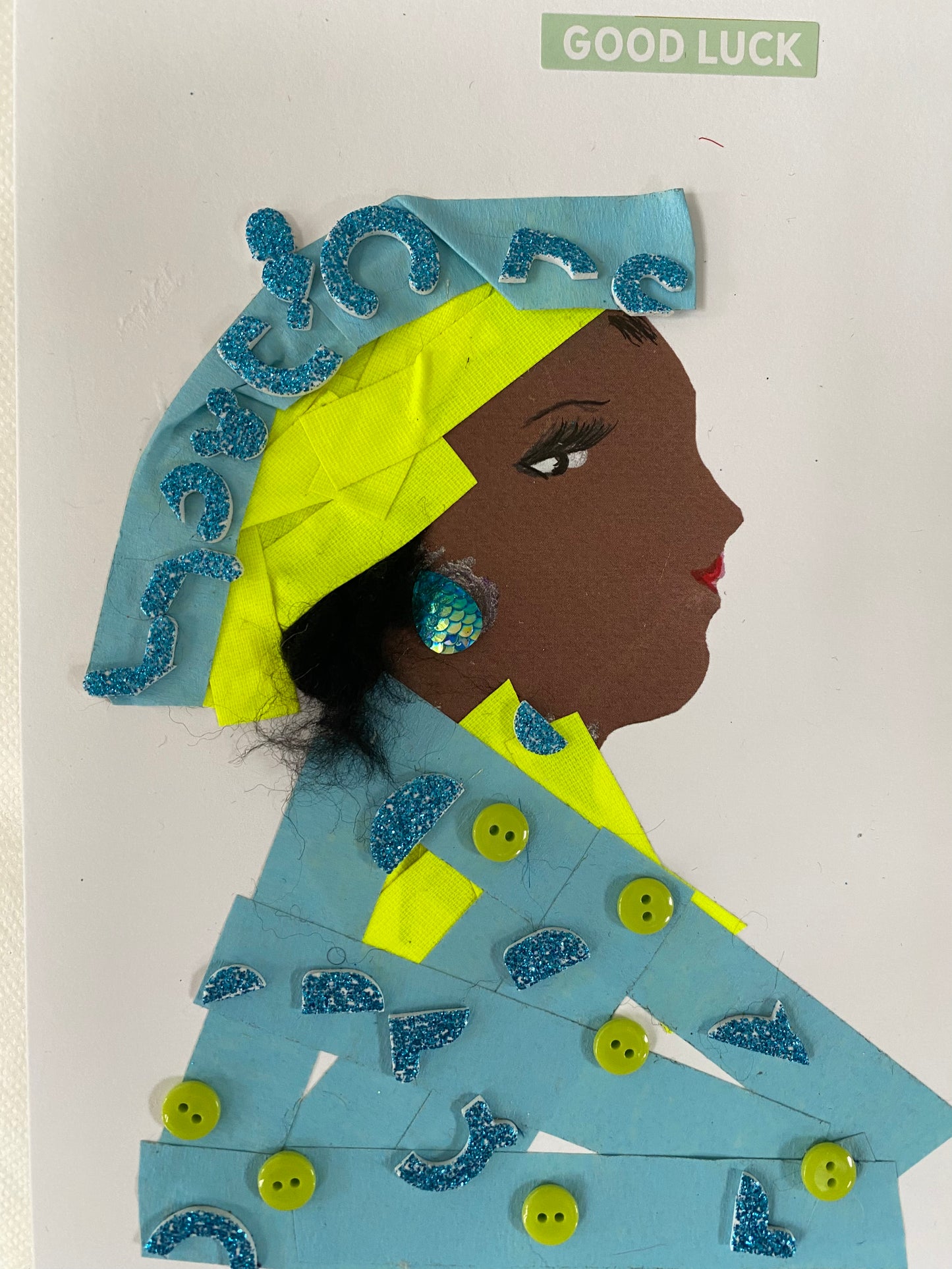 I designed this card of a woman named Blakeley Blue. She has a brown skin tone and is wearing a blue and neon yellow sparkly hat. She wearings a matching blue blouse with green button and blue sparkles. She wears blue earrings and in the corner it says good luck.