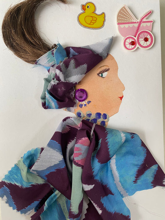 I designed this card of a woman named Gretchen Gratuitous. She has a white skin tone and is wearing a blue and purple pattern hatinator. She wears a matching blue and purple blouse. She wears blue, purple, and silver jewellery. In the corner there is a pink stroller and a yellow duck.