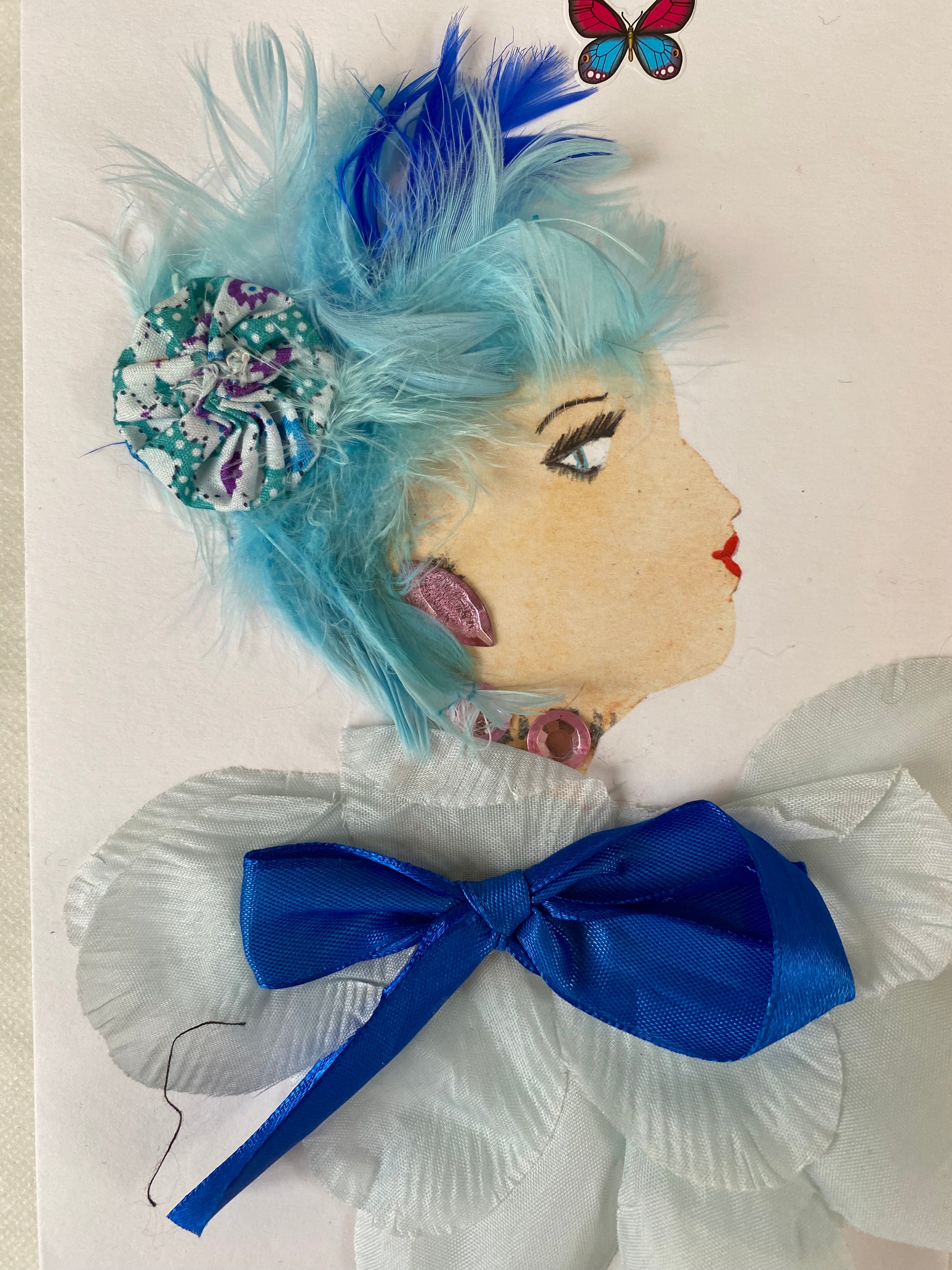 I designed this card of a woman named Bella Blue. She is white skin tone and wears a floral clip and a baby blue blouse adorned with a delicate blue ribbon. Her look is completed by whimsical pink jewellery and a majestic red and blue butterfly in the sky. Perfect for any special occasion.