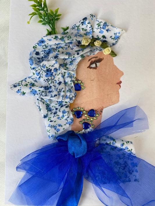 I designed this handmade card of a woman named Dr. Borough Bright. She has a white skin tone and is wearing a blue floral head wrap. She wears a matching blouse with a big blue bow in the middle. She wears blue and silver jewellery.