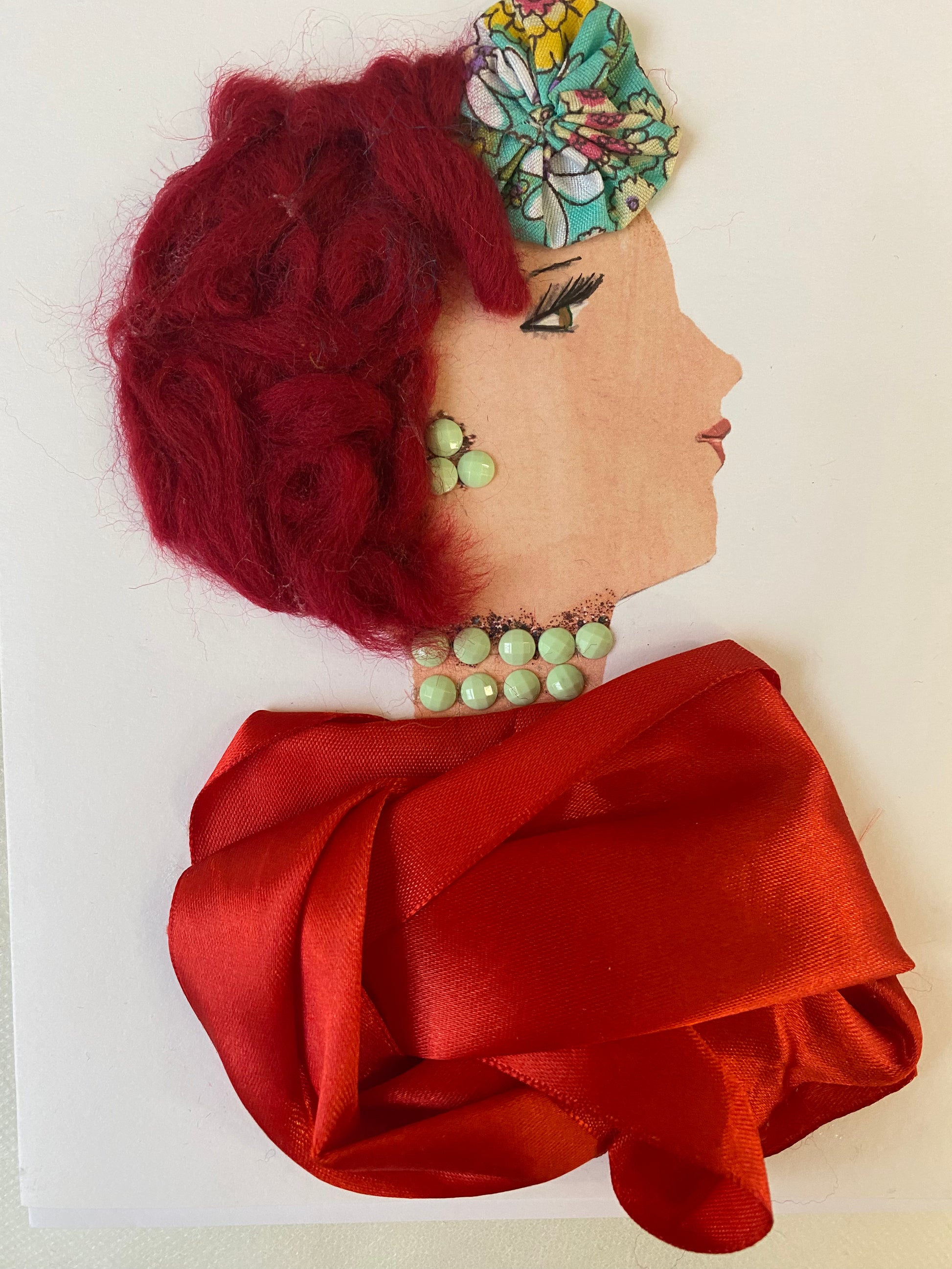 I designed this card of a woman named Gallery Red. She has a white skin tone and wears blue floral head piece in her redish purple hair. She wears a silk red blouse. She wears green gems as her jewellery. 